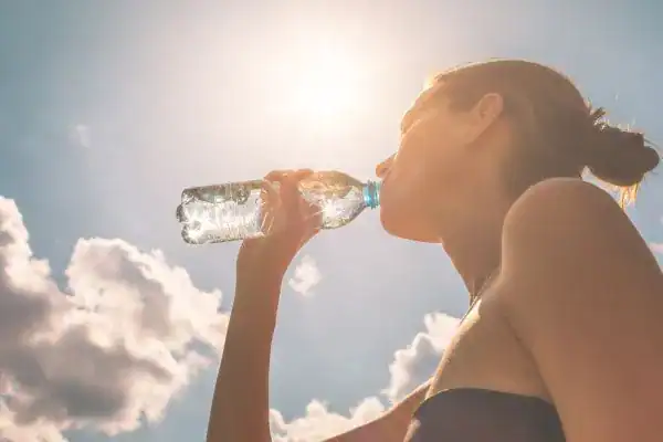 Hydration: The Secret Ingredient for a Toned Stomach and Enhanced Fitness 3 Image of woman drinking water to hydrate Northamptonshire after run.