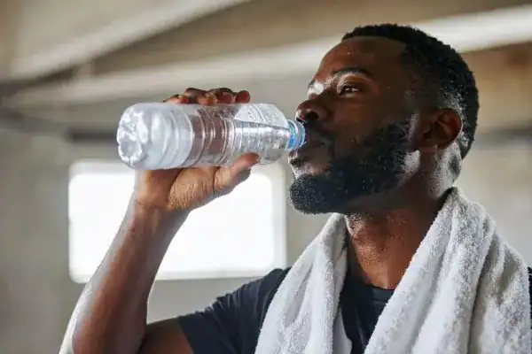 Hydration: The Secret Ingredient for a Toned Stomach and Enhanced Fitness 1 Image of man drinking water to improve hydration Northamptonshire after work out.